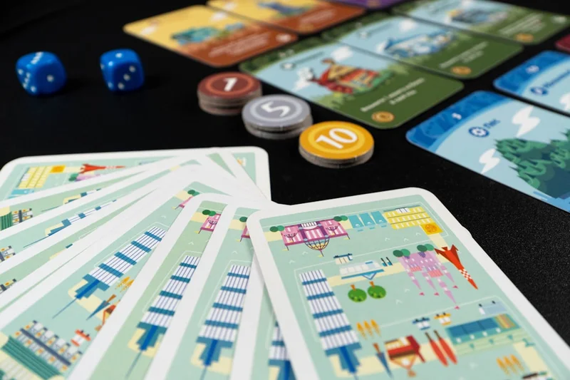 A top-down view of randomly selected cards and components from Machi Koro and its expansion.