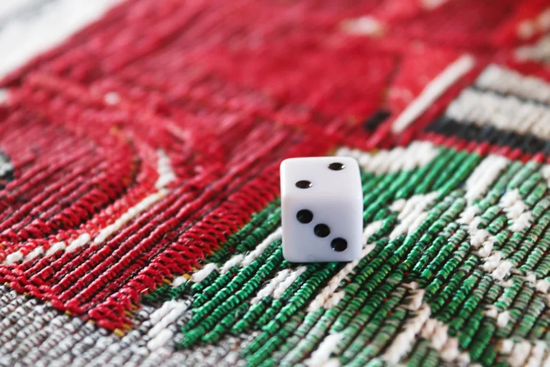 A single die resting on a cloth Christmas decoration.
